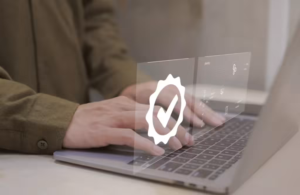 Osoba pracująca na laptopie, nad którą unosi się duża, świecąca ikona pieczęci certyfikatu z symbolem zatwierdzenia, symbolizująca proces Extended Validation.