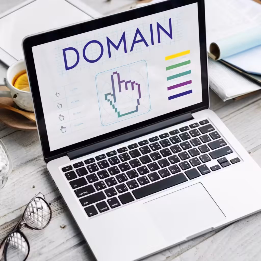 Laptop z ekranem wyświetlającym napis "DOMAIN" i ikonę klikającej dłoni, symbolizując zarządzanie domenami internetowymi.